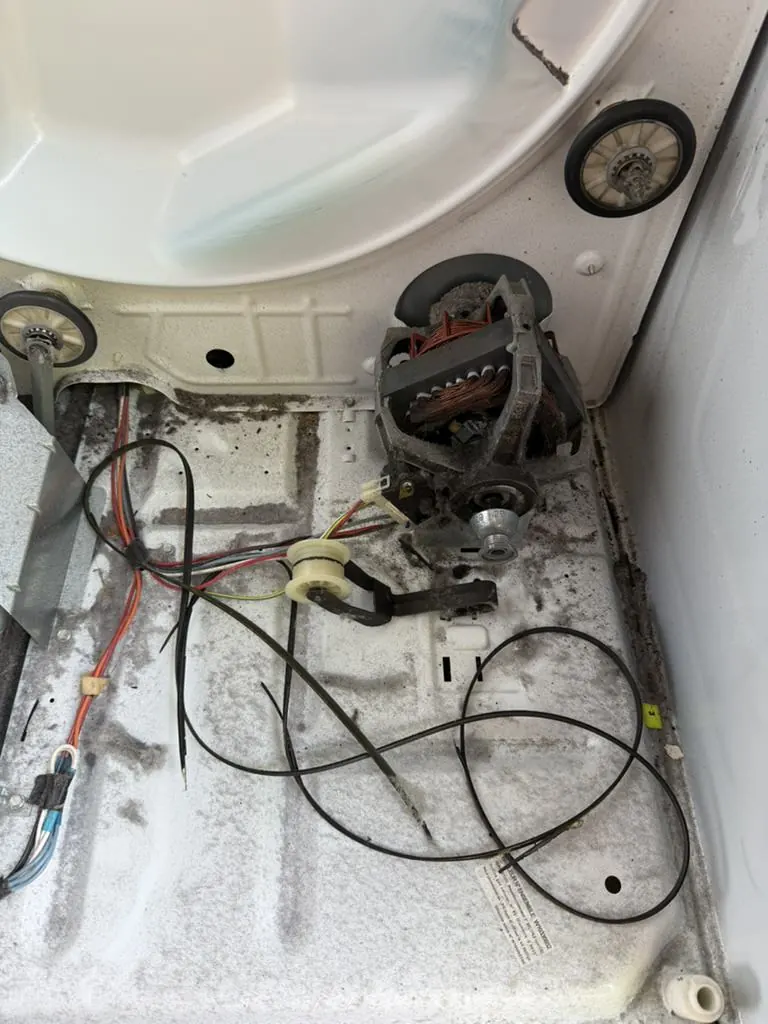 Broken dryer drive belt inside dryer with drum and motor exposed