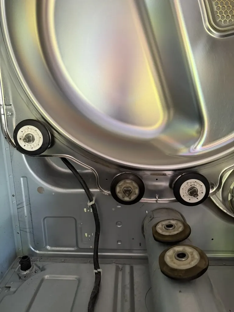 Worn and seized dryer drum support rollers inside an opened dryer